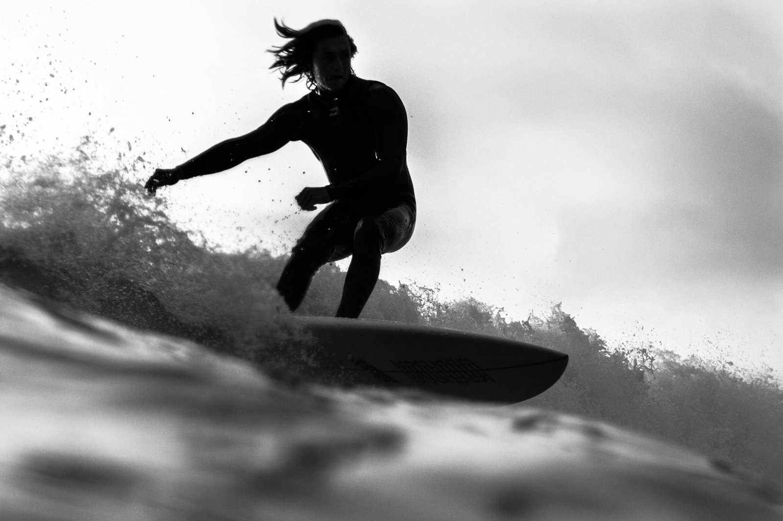 Black and white shot of a surfer bursting through the spray