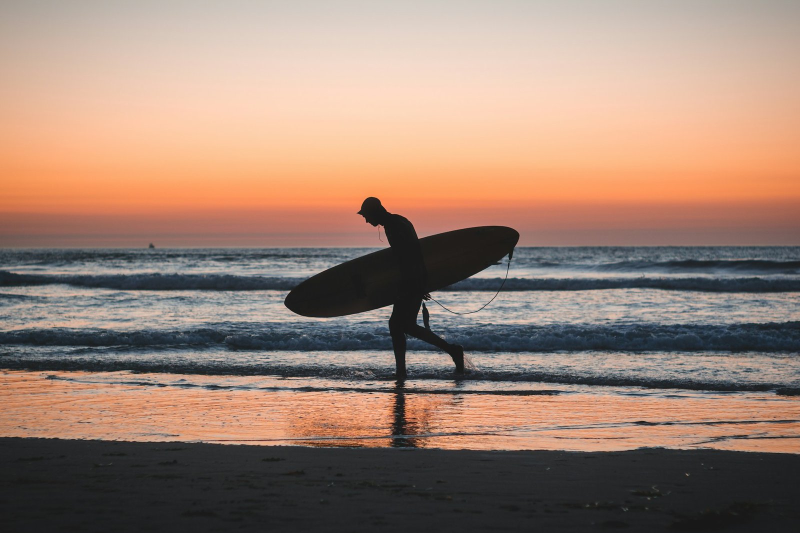 Silhouette of a surfer holding his board by the sea