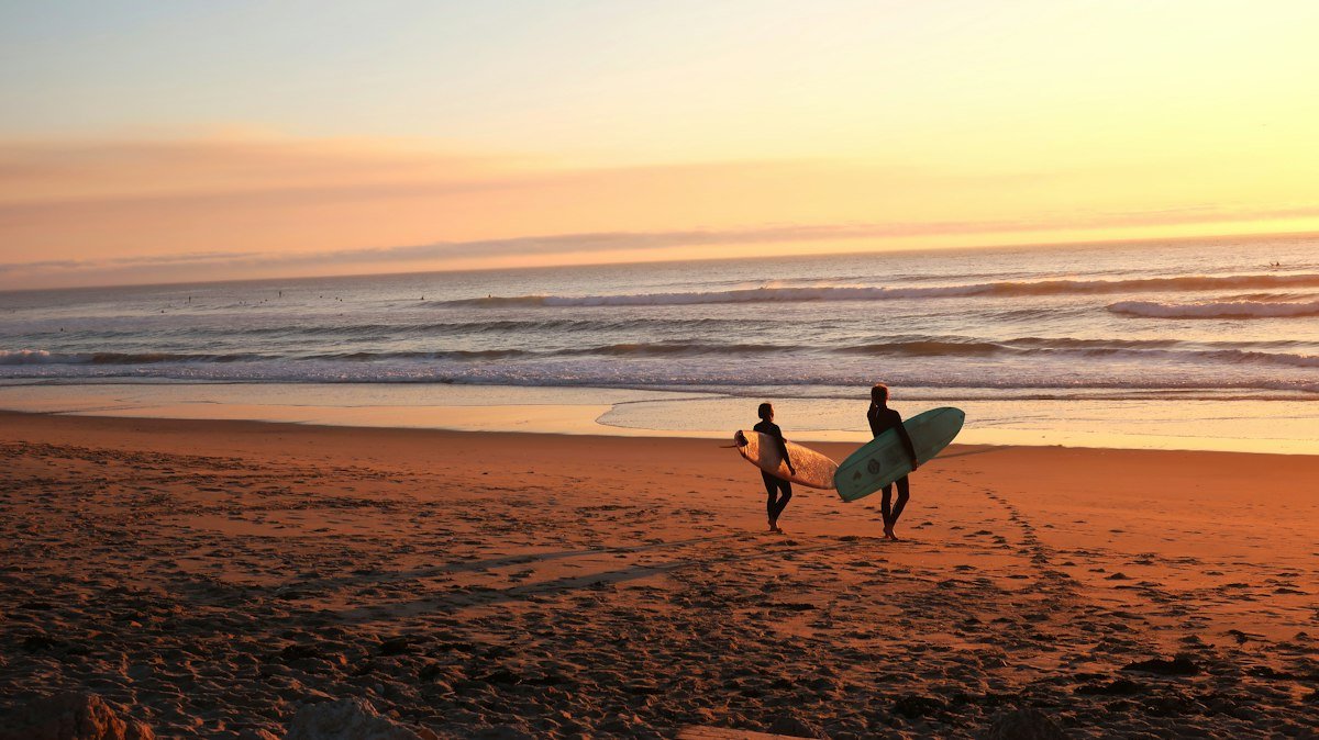 Two surfers walking on the sand towards the water