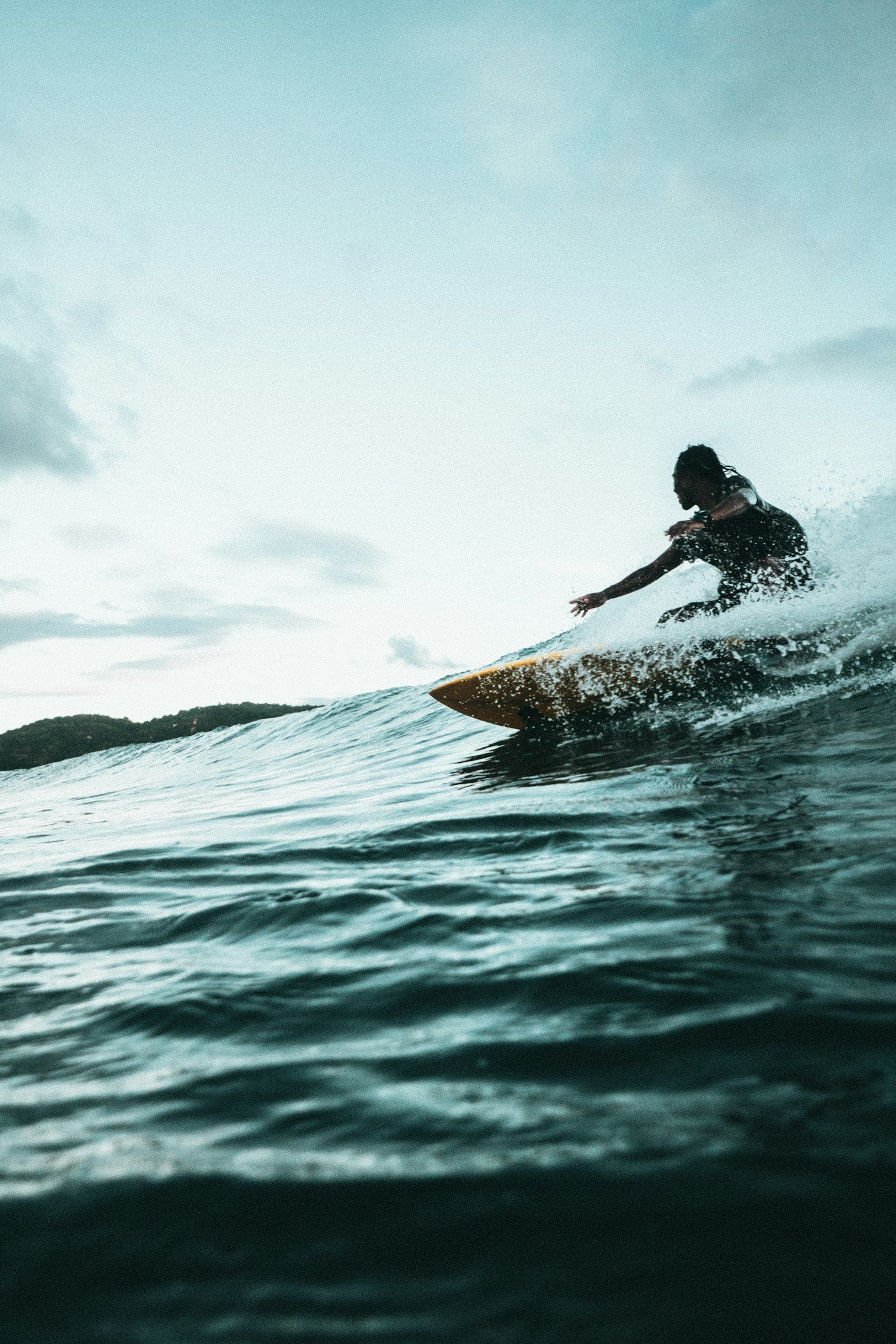 Surfer leaning into a turn on a teal wave