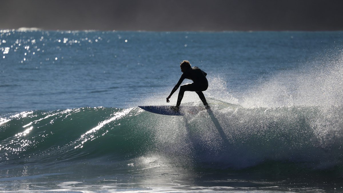 Surfer silhouette on a backlit wave
