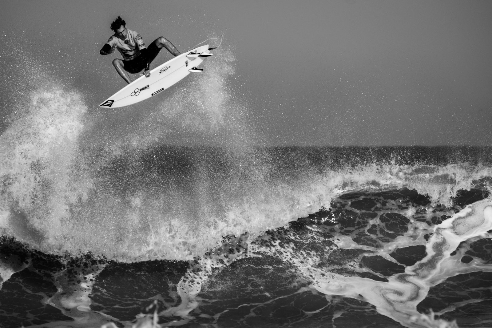 Black and white shot of a surfer flying above the lip