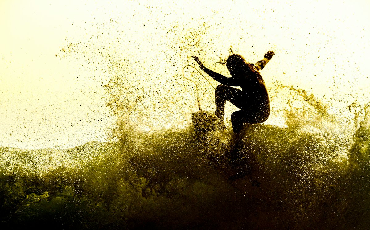 Backlit surfer in the spray of a big wave