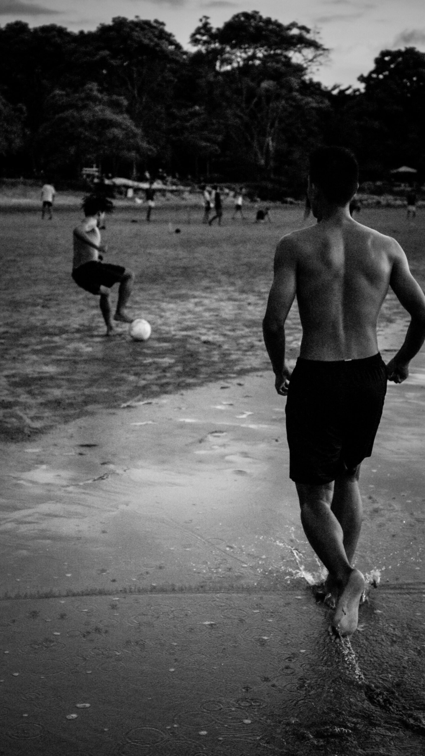 Black and white shot of a football match on a local pitch