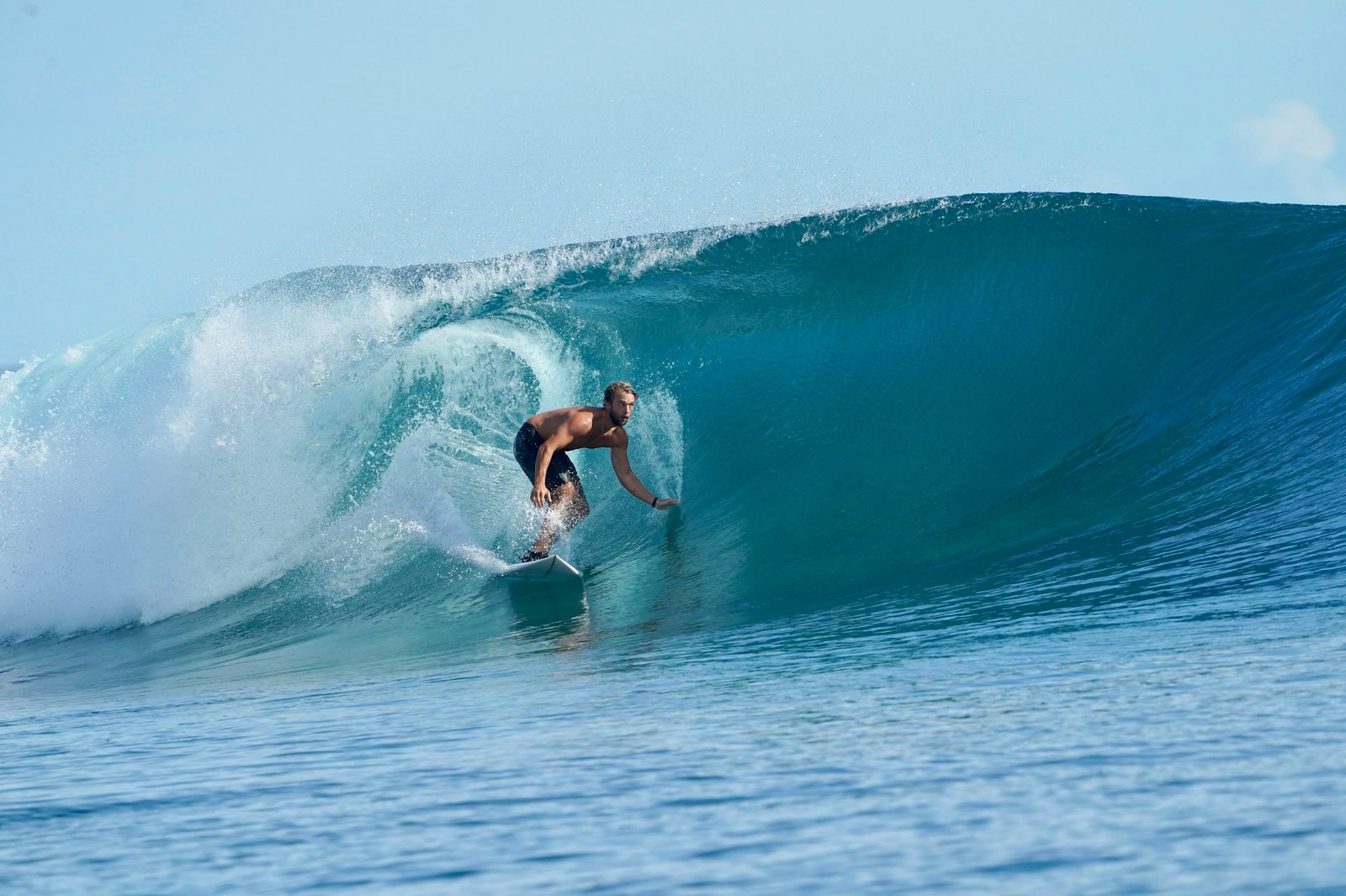 Surfer standing tall inside a blue barrel