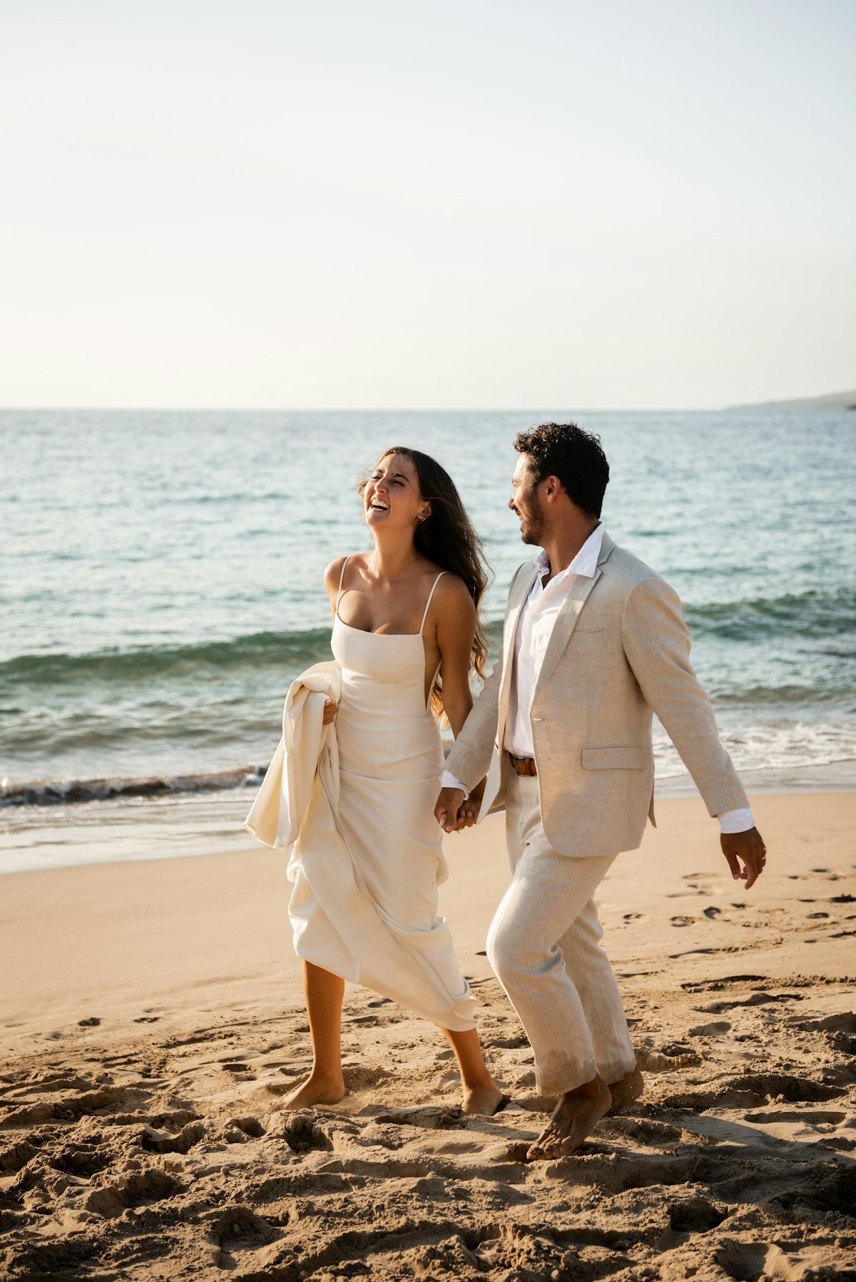 Newlyweds running along the beach