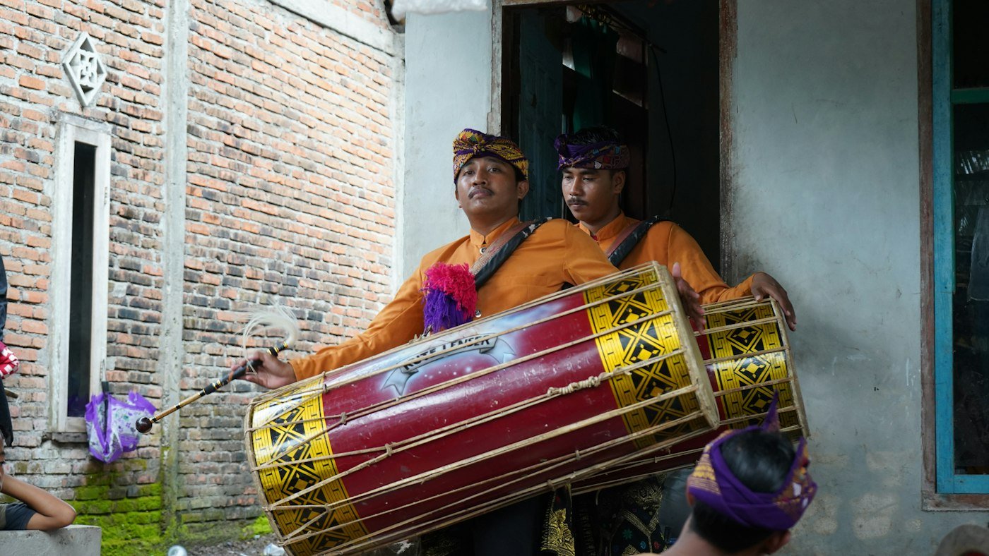 Two men playing a large traditional drum outdoors
